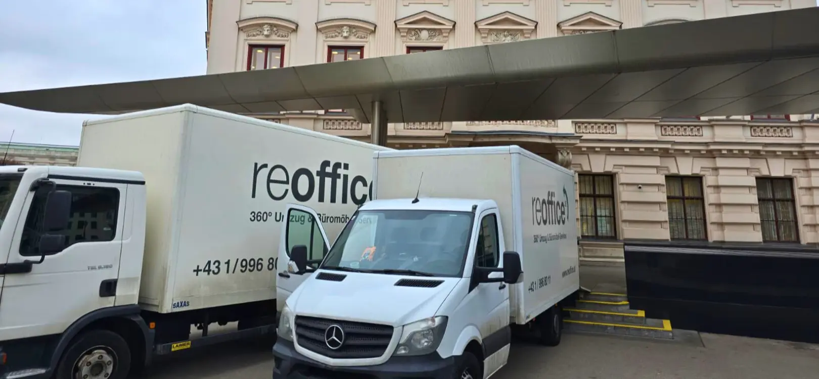 Zwei reoffice Umzugswagen geparkt vor einem historischen Gebäude.
