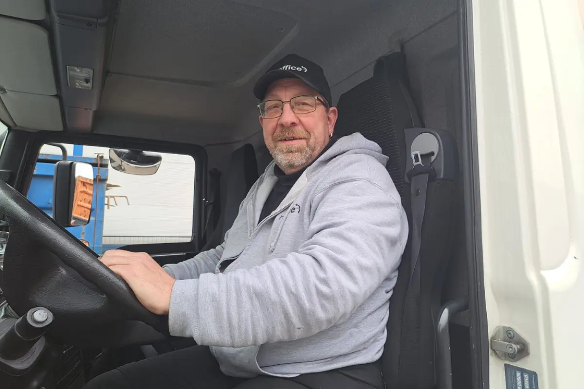 Ein lächelnder Reoffice-Mitarbeiter am Steuer eines Lieferwagens.