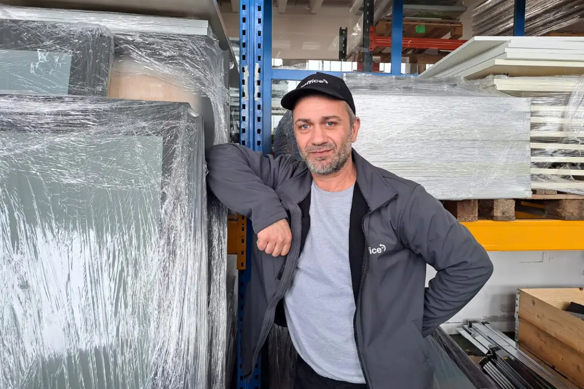 Ein lächelnder Mitarbeiter von Reoffice mit Kappe im Lagerbereich