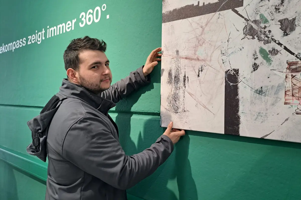 Ein Reoffice-Mitarbeiter hängt ein Bild im Büro auf.
