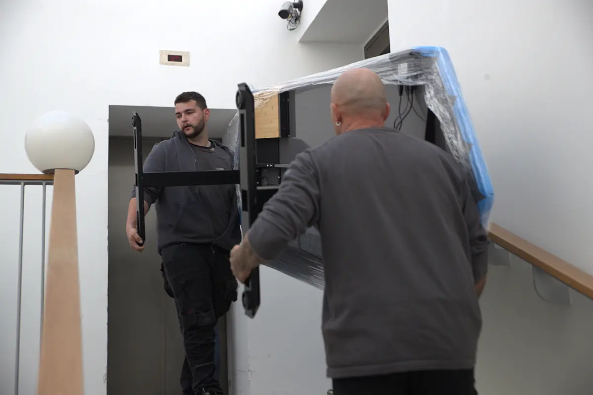 Zwei reoffice Mitarbeiter tragen einen Tisch durch ein Treppenhaus.