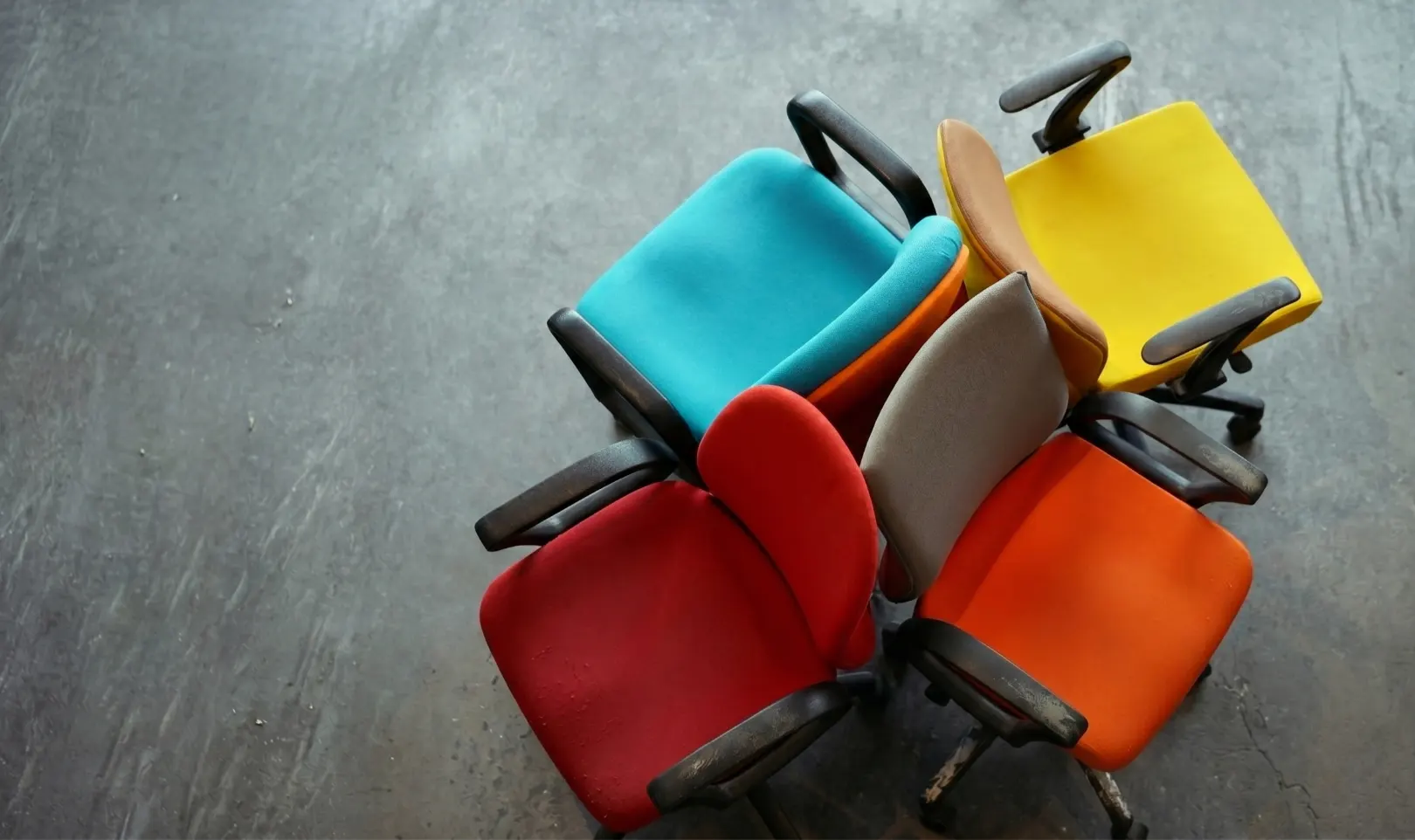 Gebrauchte, abgenutzte Bürostühle in verschiedenen Farben, bereit für die fachgerechte Entsorgung oder das Recycling.