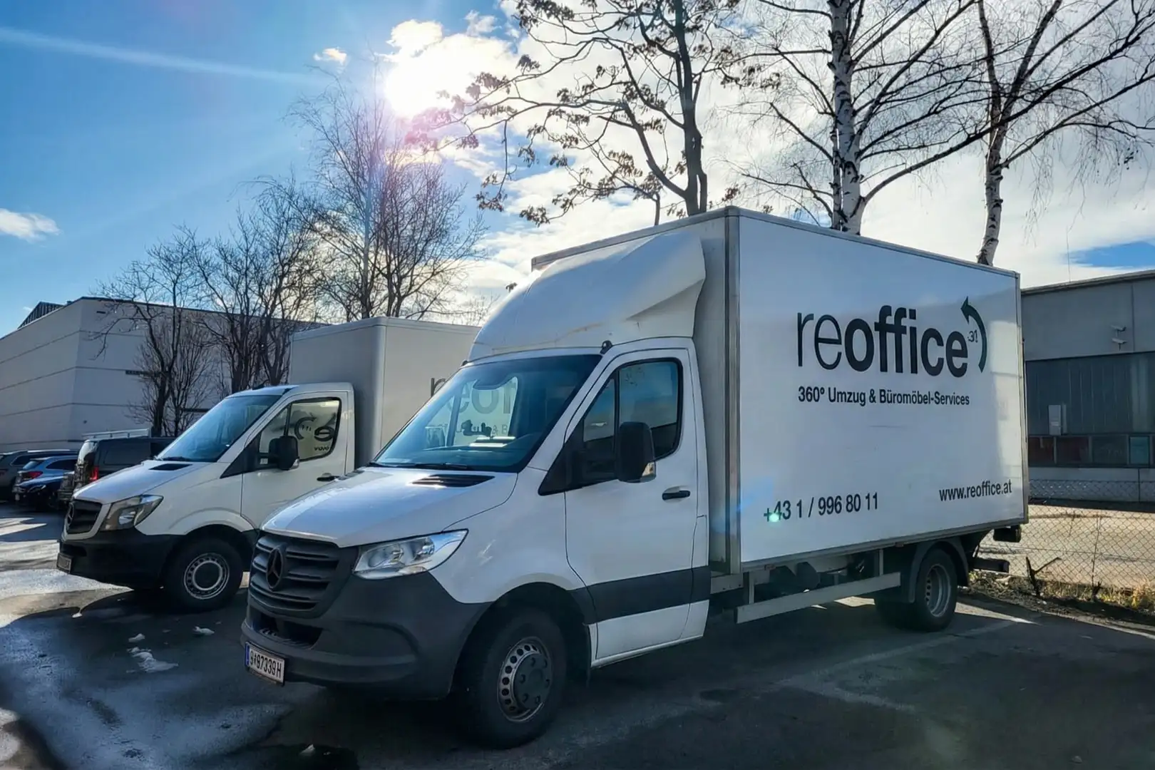 Zwei reoffice Transporter auf einem Parkplatz bei Sonnenschein.